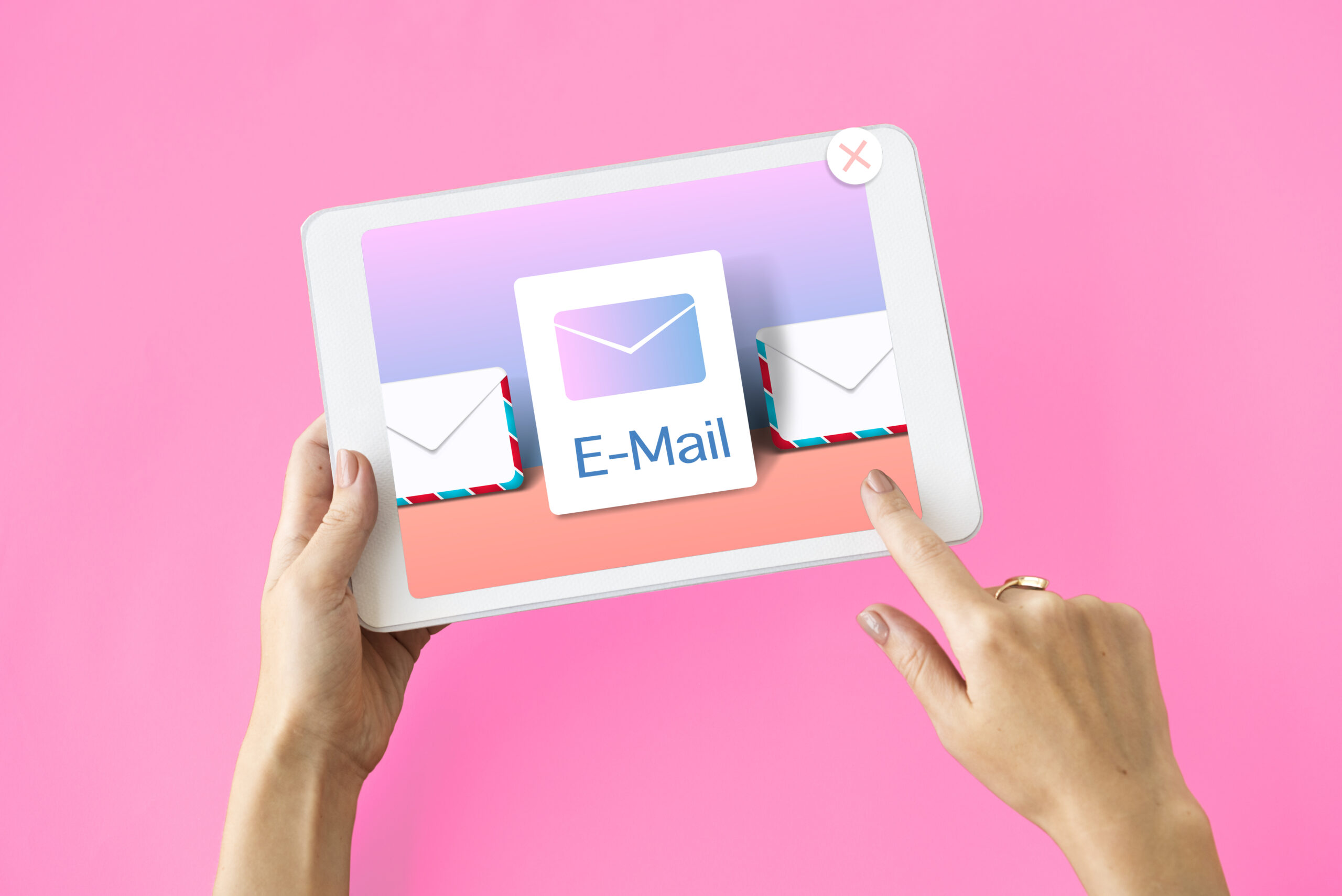 As mãos de uma pessoa segurando um tablet com o atalho de e-mail na tela