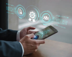 Imagem das mãos de um homem vestido de terno usando um smartphone com ícones flutuantes acima para ilustrar o post chamado "O que é PWA?"
